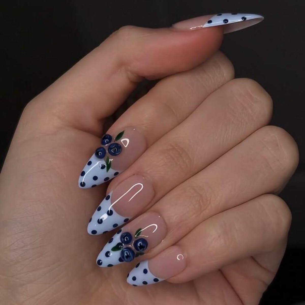 Bright electric blue polka dot french nails on almond glossy acrylics for music festivals.