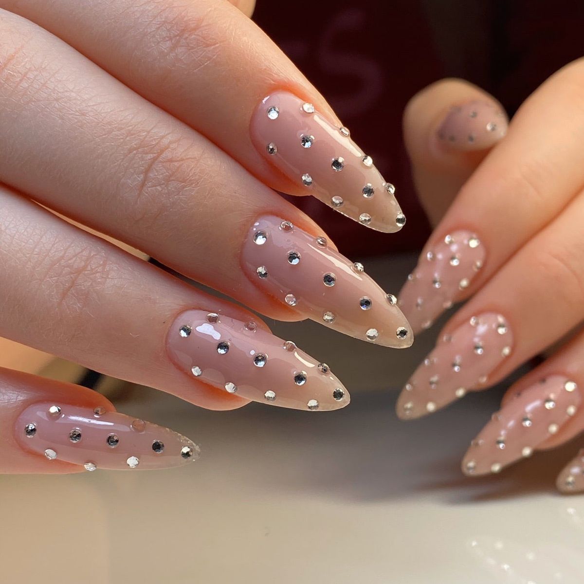 Long almond champagne shimmer rhinestone nails with glossy gel finish for evening gala events.