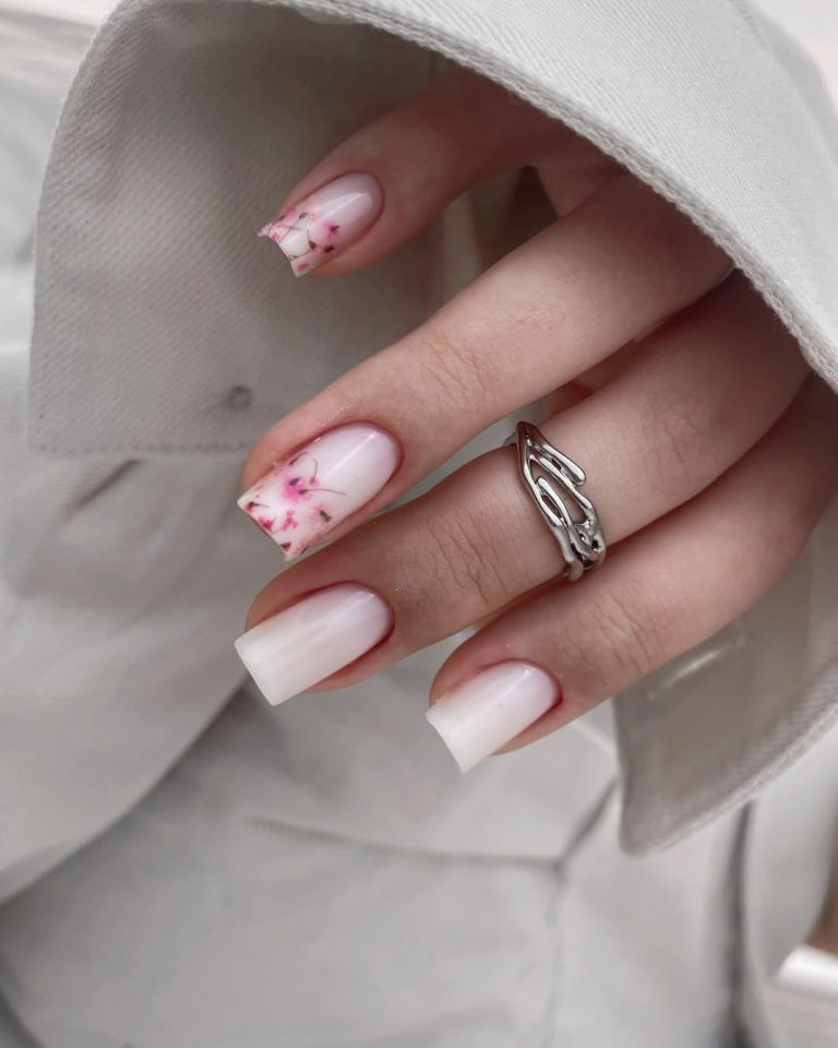 Oval shaped milky white nails with delicate floral nail art for spring gatherings.