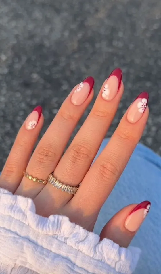 Delicate French tip nails with light pink and beige tips with white floral designs