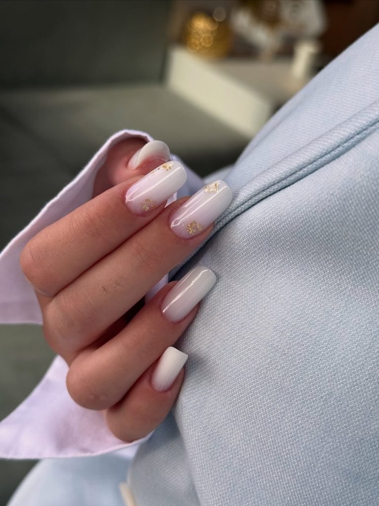 Squoval shaped milky white nails with delicate gold leaf flakes for New Year's Eve.