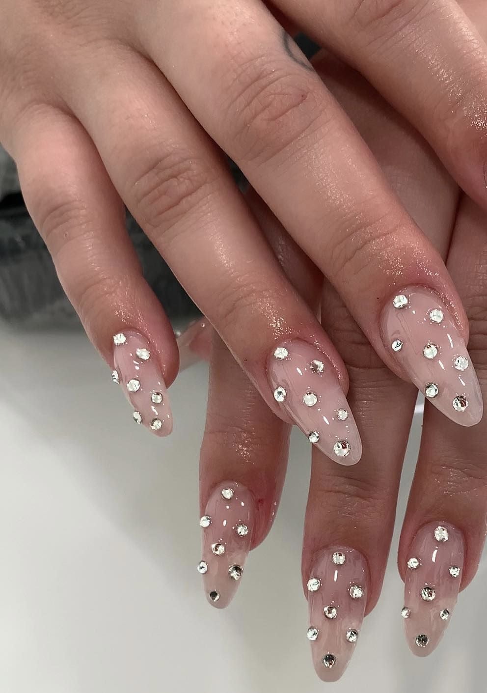 Medium almond glazed pearl rhinestone nails with chrome gloss finish for luxury vacations.