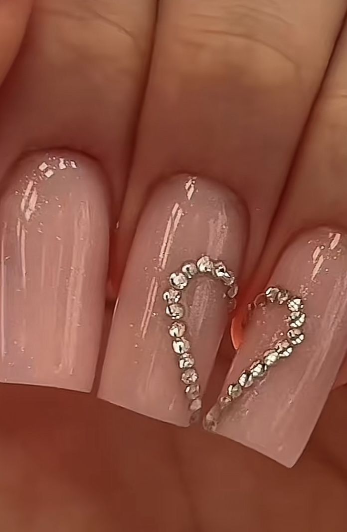 Medium almond baby pink heart rhinestone nails with glossy topcoat for romantic dates.
