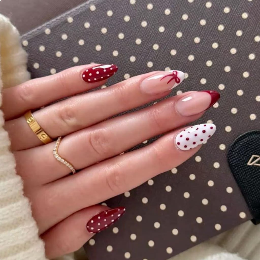 Deep ruby red polka french nails on oval glossy polish for festive holiday season.