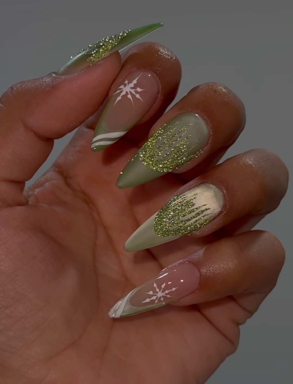 Sage Green Stiletto Nails With Glitter Drips And Snowflakes