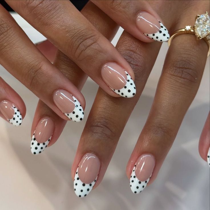 High contrast white polka french tip nails on almond glossy base with black dots.
